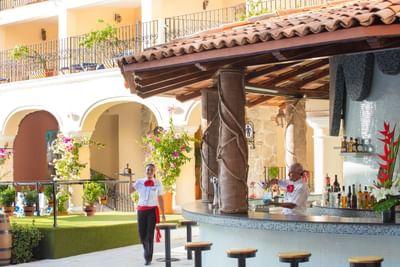 Bar al aire libre con techo de teja y personal de servicio en uniforme en Los Arcos Suites
