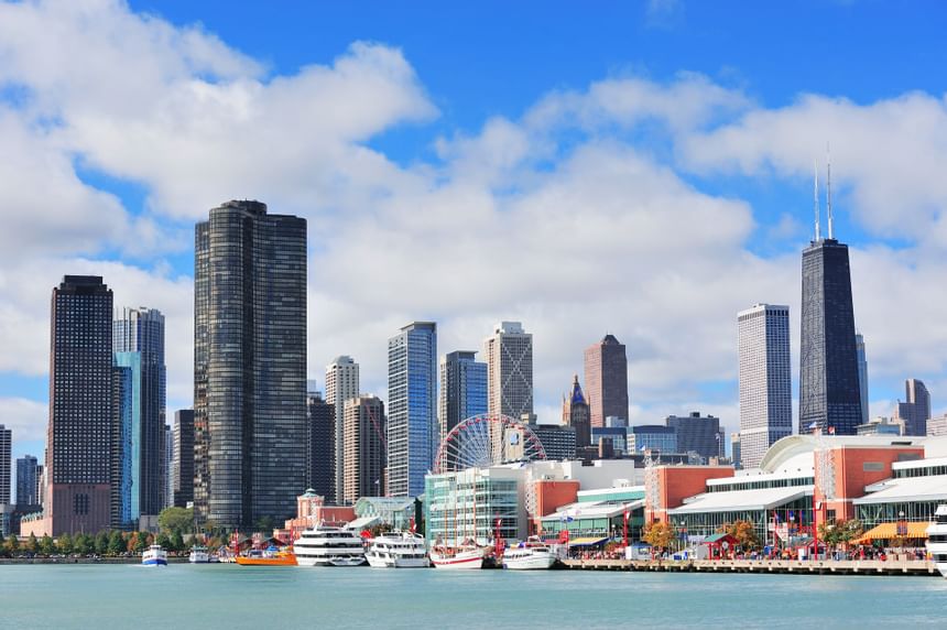 Landscape view of Navy Pier with boats by Lake Michigan and the Chicago skyline beneath blue skies near Hotel Saint Clair
