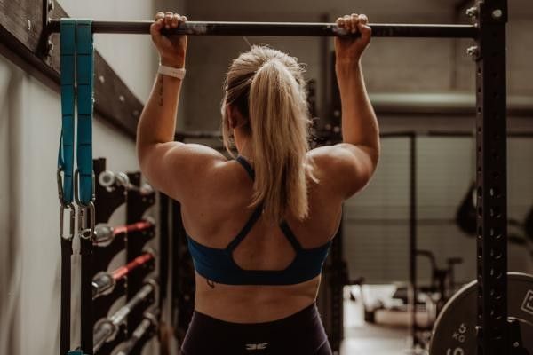 Woman performing a traditional chin up at the gym.