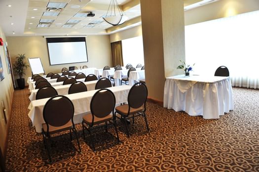 Rows of tables and chairs facing projector screen