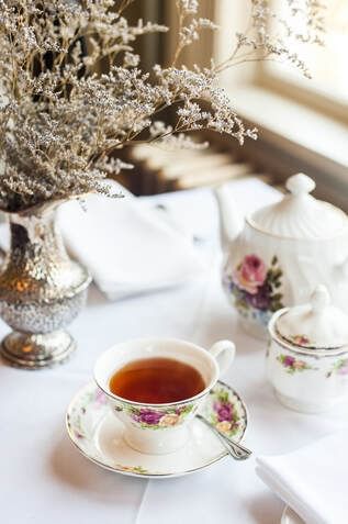 Flower vase by a table served with tea in Pendray Tea House at Pendray Inn & Tea House