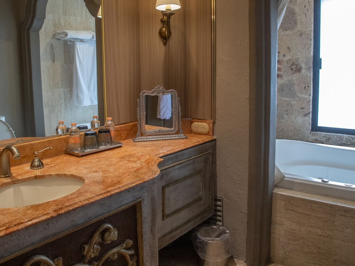 Baño elegante con tocador de mármol, tina junto a ventana y detalles en piedra en Quinta Real Guadalajara