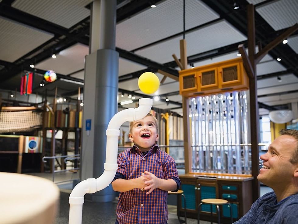 A man and child playing with a ball in Telus Spark Kids Museum near Hotel Clique Calgary Airport