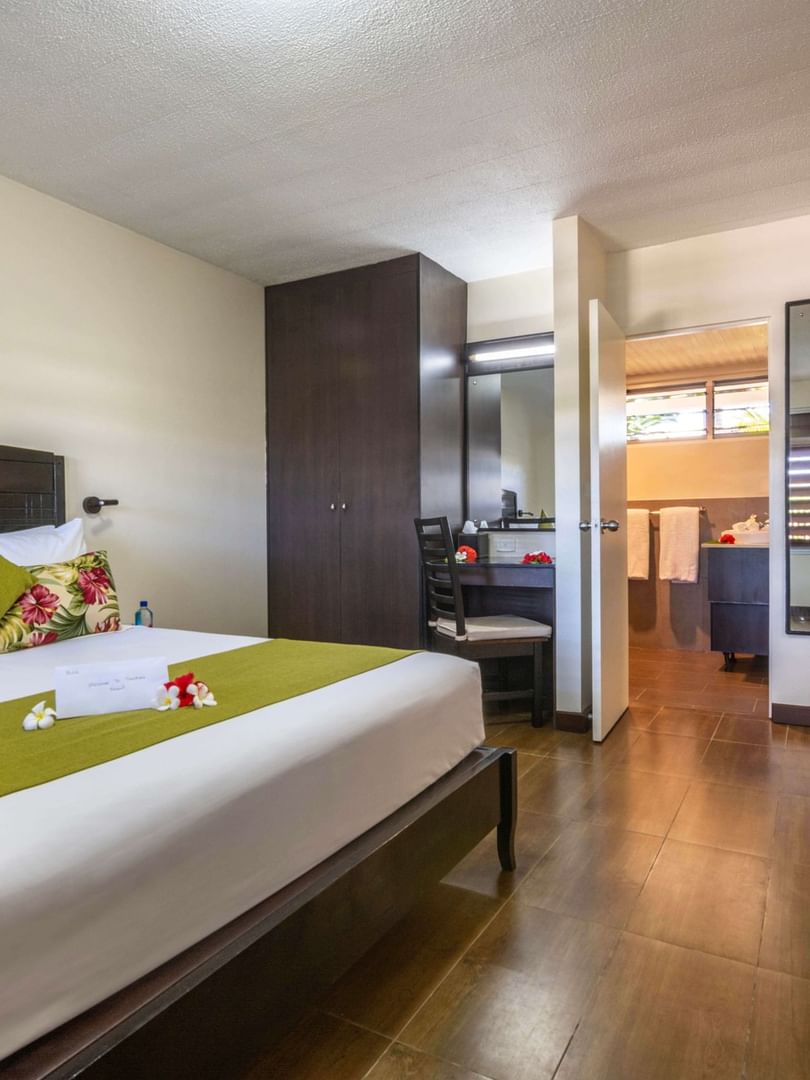King bed with green runner by a dark wardrobe in Executive Suite at Tokatoka Resort - Fiji International Airport, Nadi