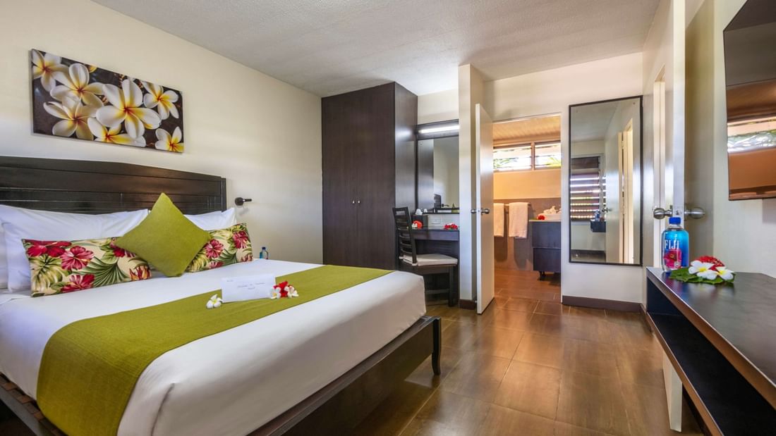 King bed with green runner by a dark wardrobe in Executive Suite at Tokatoka Resort - Fiji International Airport, Nadi