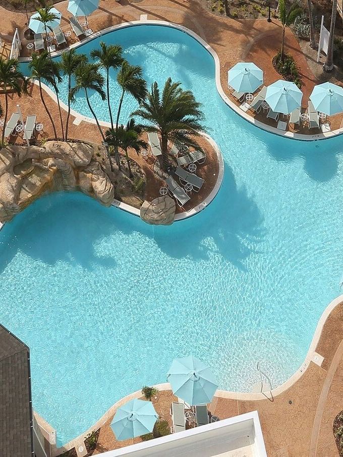 Blue umbrellas by a winding pool surrounding a rock feature near Warwick Paradise Island Bahamas