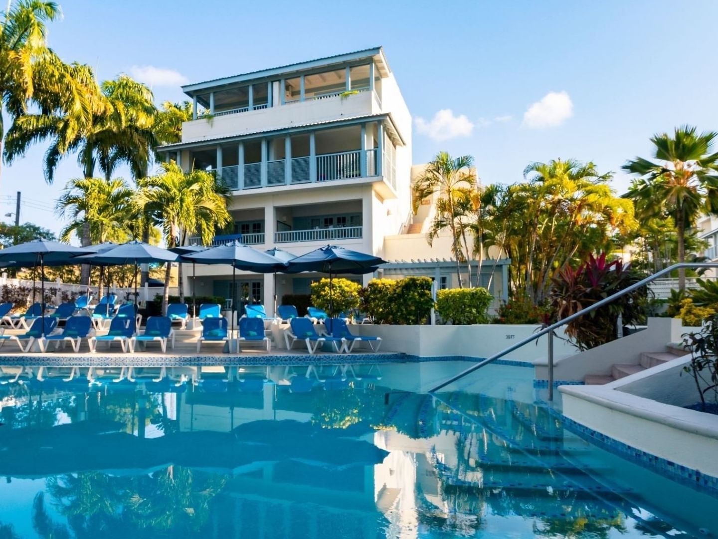 Blue pool with lounge chairs and umbrellas at Savannah Beach Hotel.