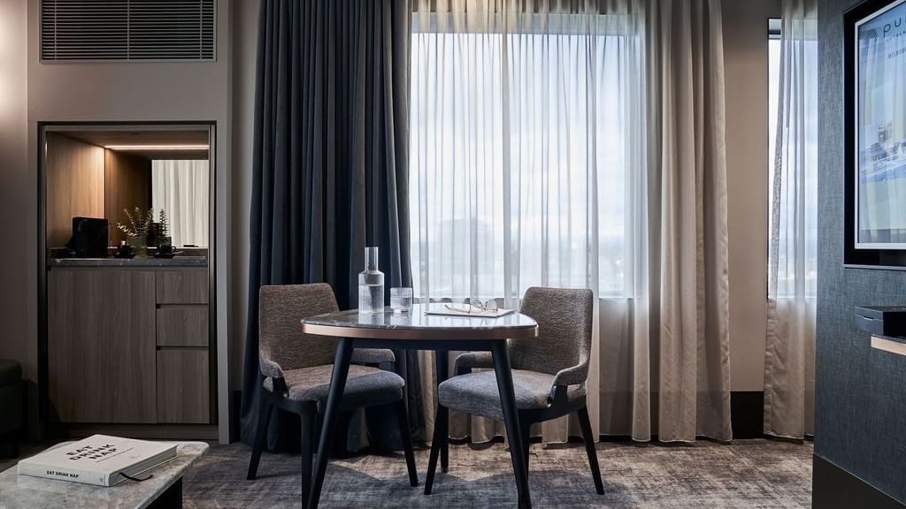 Superior Suite with dining table, layered curtains, and modern furnishings at Pullman East Melbourne