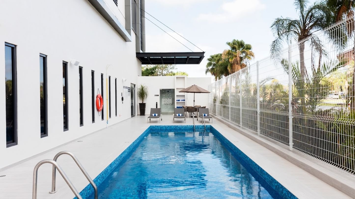 Piscina al aire libre en el Fiesta Inn Express Cancún Cumbres con camastros; hoteles en Cancún con piscinas privadas