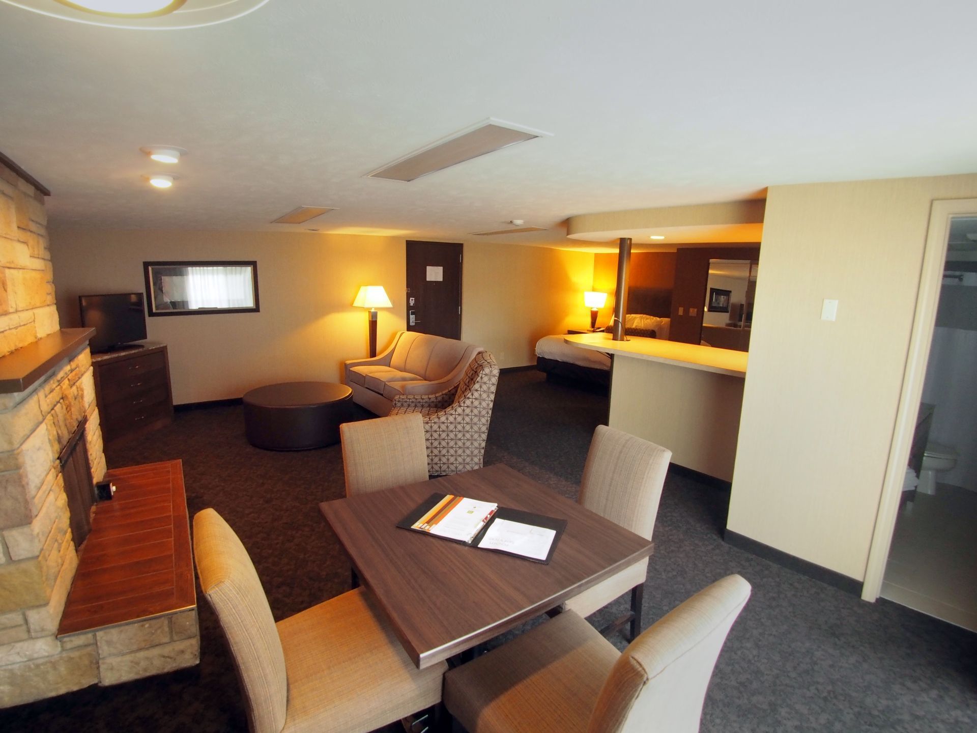 Junior Studio Suite with queen bed, sofa bed, dining table, and fireplace at Evergreen Resort in Cadillac.