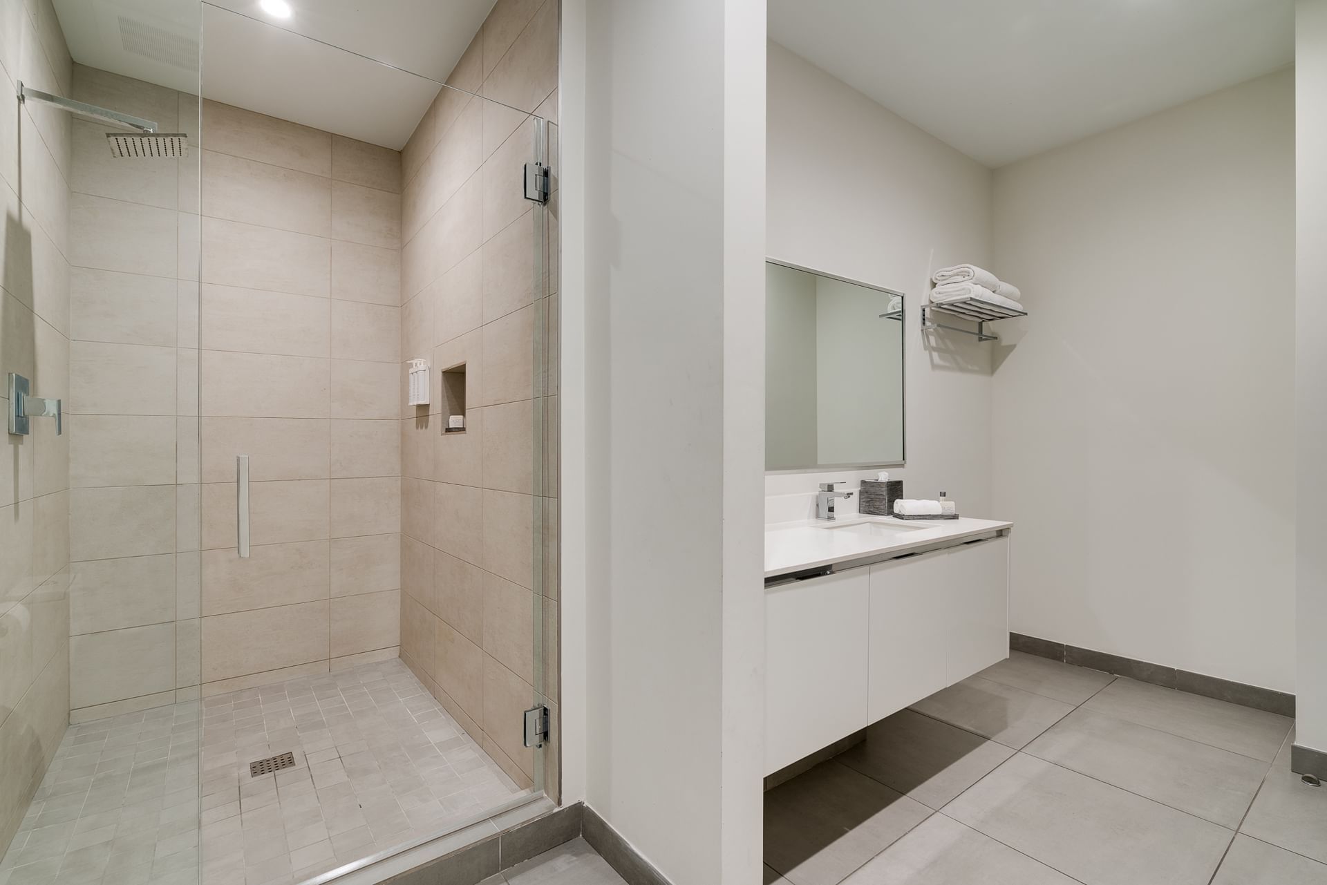 A modern bathroom with a separate glass-enclosed shower and a floating sink with a mirror.