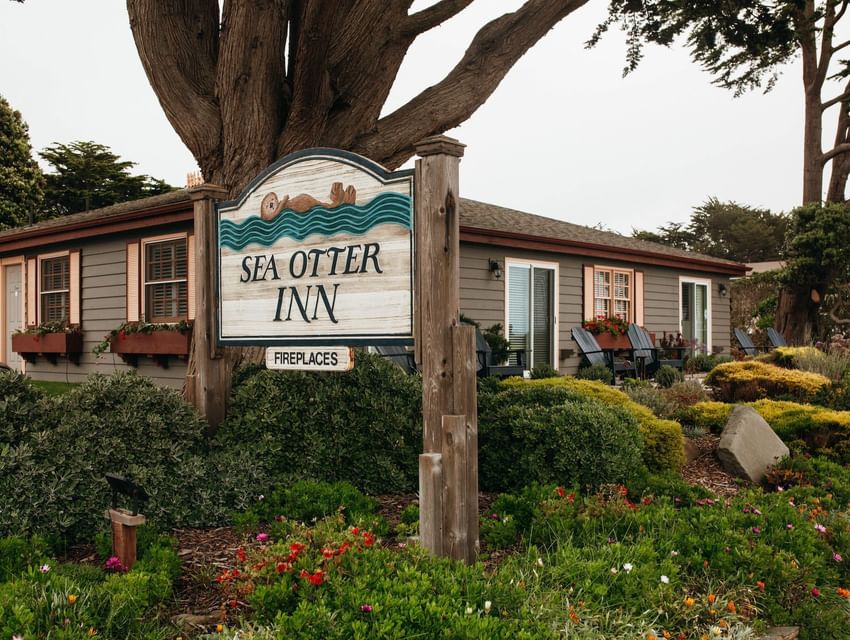 Sea Otter Inn sign in front of a house with garden and chairs outside.