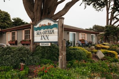 Sea Otter Inn sign in front of a house with garden and chairs outside.