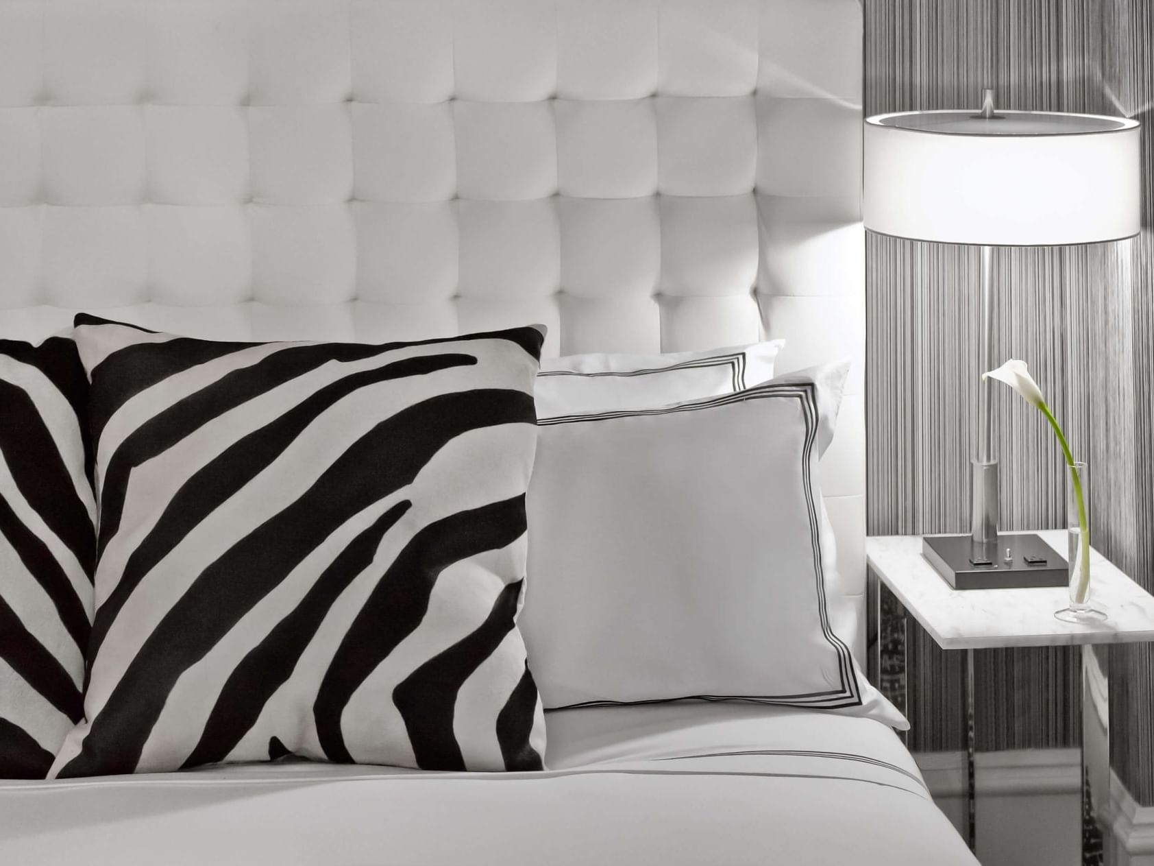Zebra print throw pillows against a white tufted leather headboard in a chic hotel room at Moderne