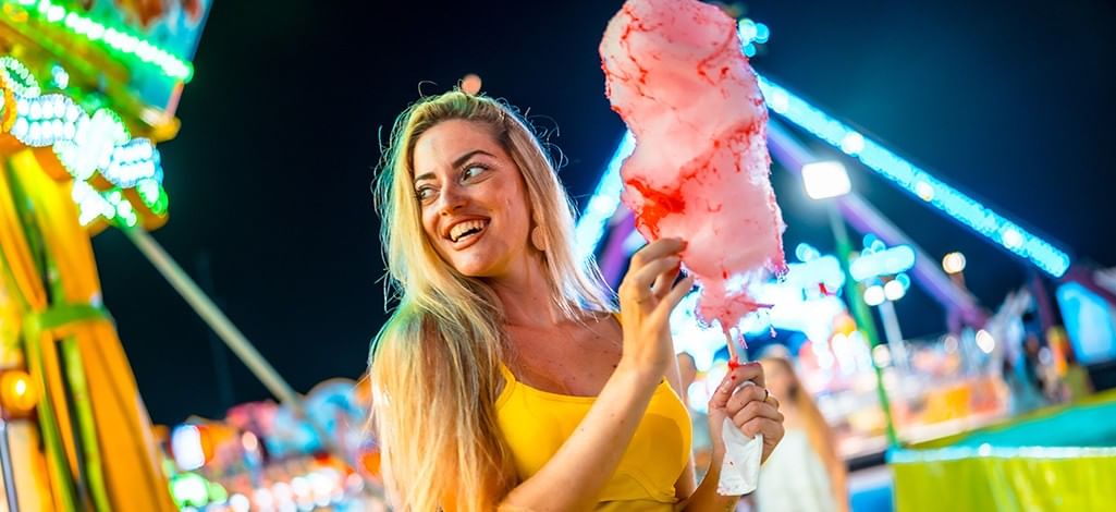 a young lady eating cotton candy at a summer night fair