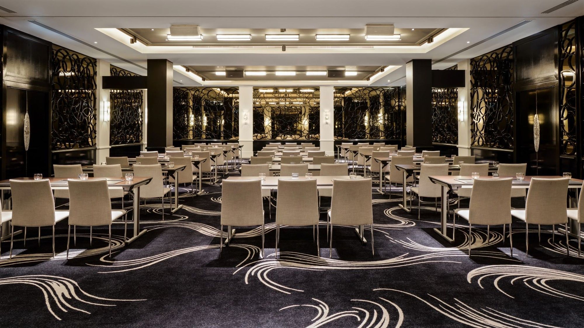 Classroom set-up with patterned carpet and dark wood paneling in the Danziger Suite at The May Fair Hotel