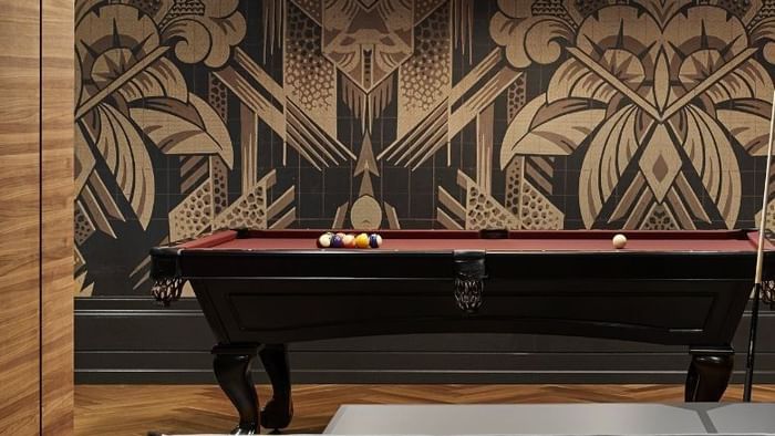 Room with pool and ping pong tables, a round ceiling light, and an ornate floral wall design.