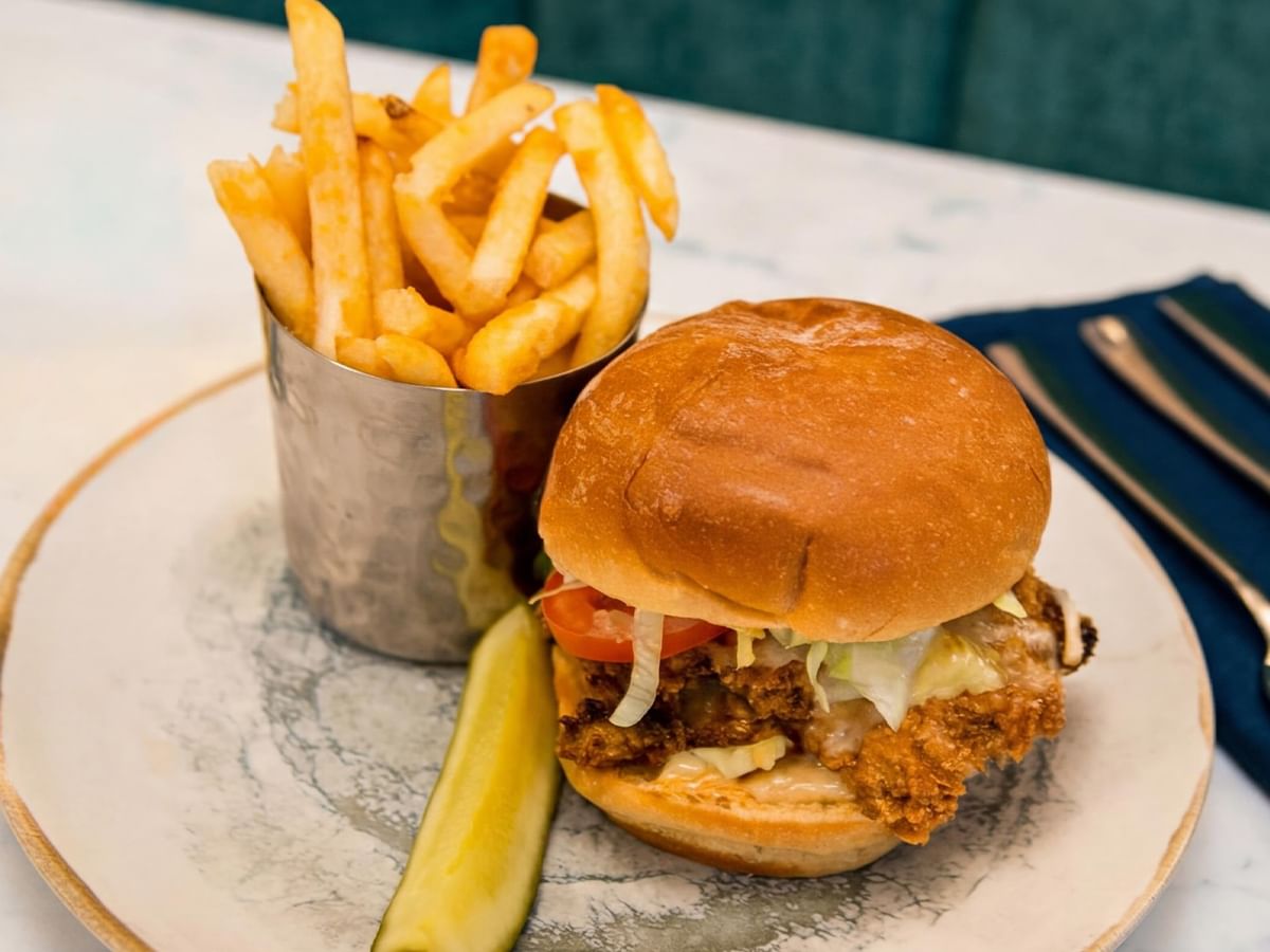 Chicken sandwich with fries and pickle.
