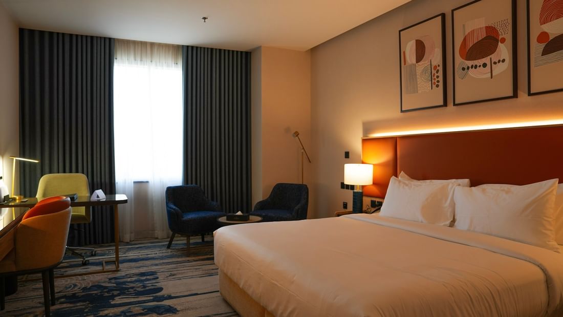 Cozy Junior Suite with a bed, chairs, desk, and large window at Warwick Hotel & Spa - Jeddah.