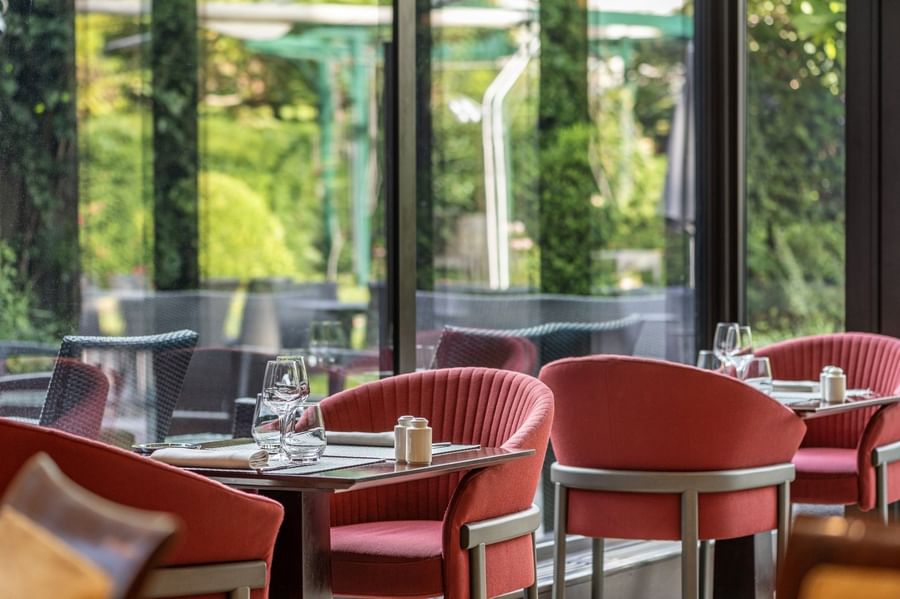 Le Lounge Restaurant interior with red chairs and modern tables set with glassware at Warwick Reine Astrid - Lyon