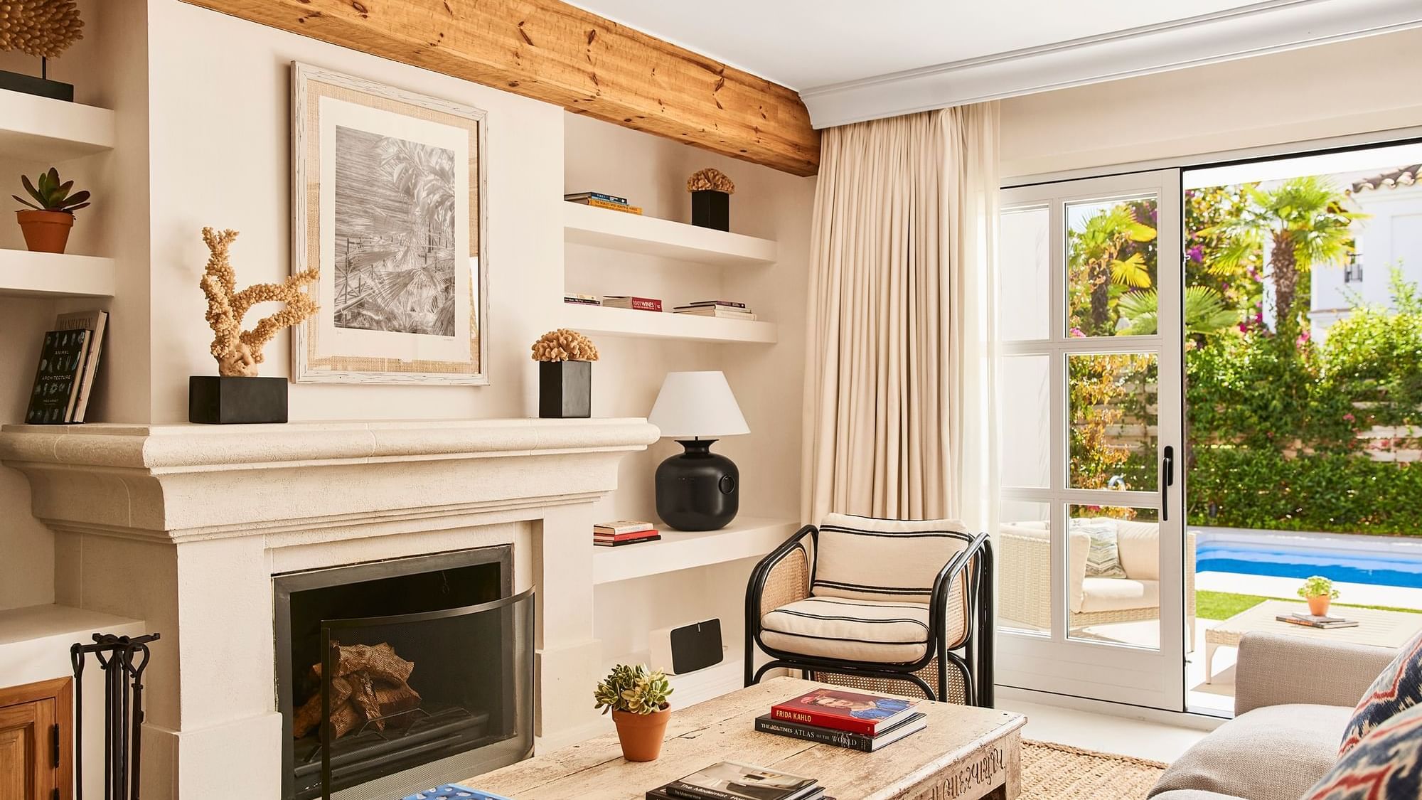 Three-Bedroom Villa living area with a fireplace, wood ceiling, & sliding doors opening to a pool at Marbella Club