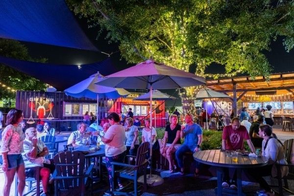 Tables, chairs, and umbrellas in an outdoor setting at Boxi Park, a great spot for families to eat in Orlando.
