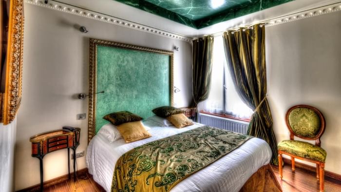 Chambre élégante avec lit, fauteuil et fenêtre à l'Hôtel Villa Aultia.