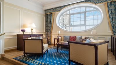 Room with large circular windows, classic furniture, and patterned blue carpet at Polonia Palace Hotel