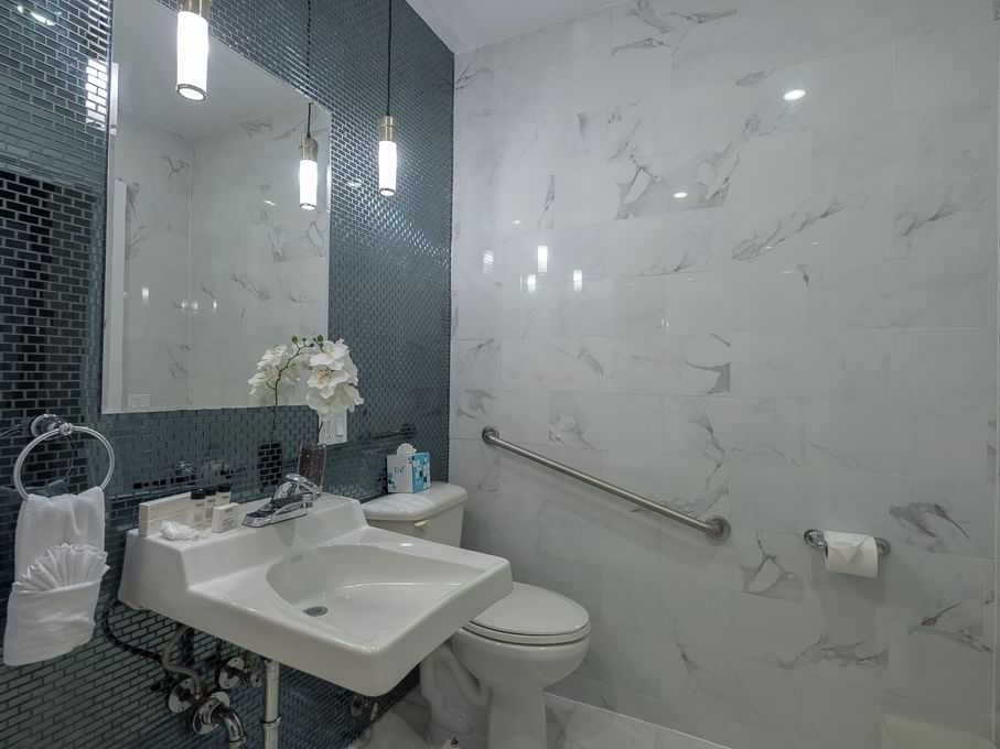 Large marble bathroom with teal tile and ADA Accessible grab bars by the toilet