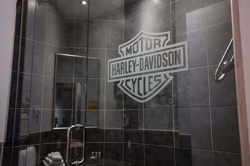 harley davidson logo painted on dark tile in glass shower