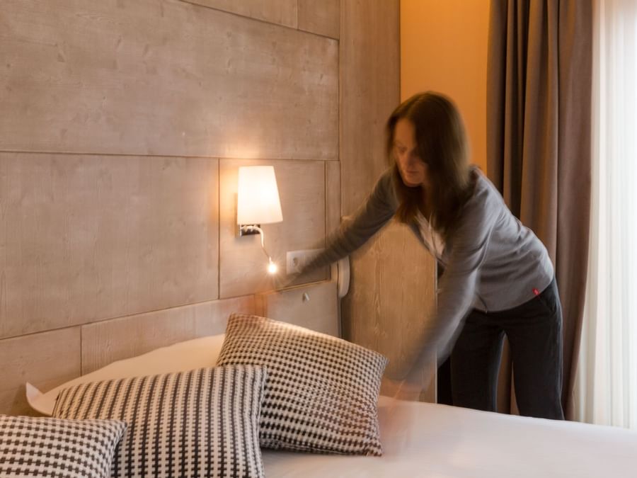 A Woman preparing a Standard Double bed at Hotel Alize