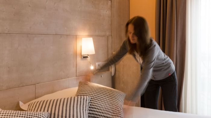 A Woman preparing a Standard Double bed at Hotel Alize