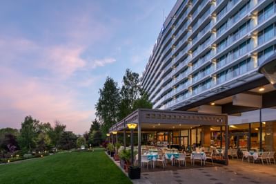 Ana Hotels Europa Eforie Nord exterior, featuring a spacious garden patio with dining tables surrounded by lush greenery