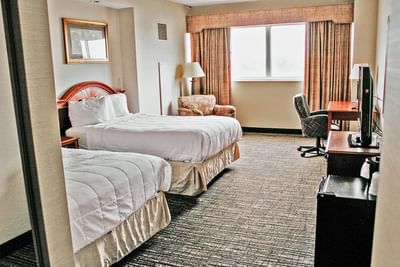 A comfortable double guest room at Hotel Topeka at City Center with two full beds and a work desk.
