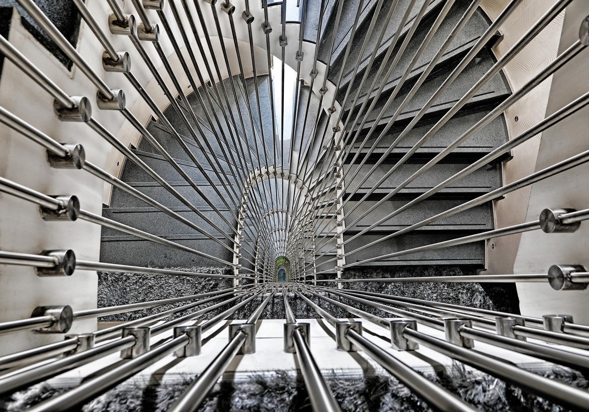 Spiral staircase with metal railings by grey steps under a bright light at Warwick Stone 55 - Beirut