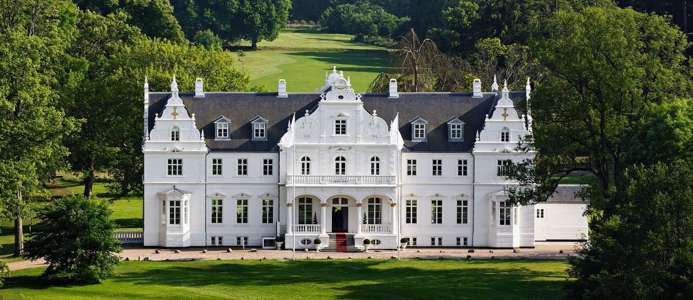 Large white estate house with green lawn and trees at Warwick Corporate