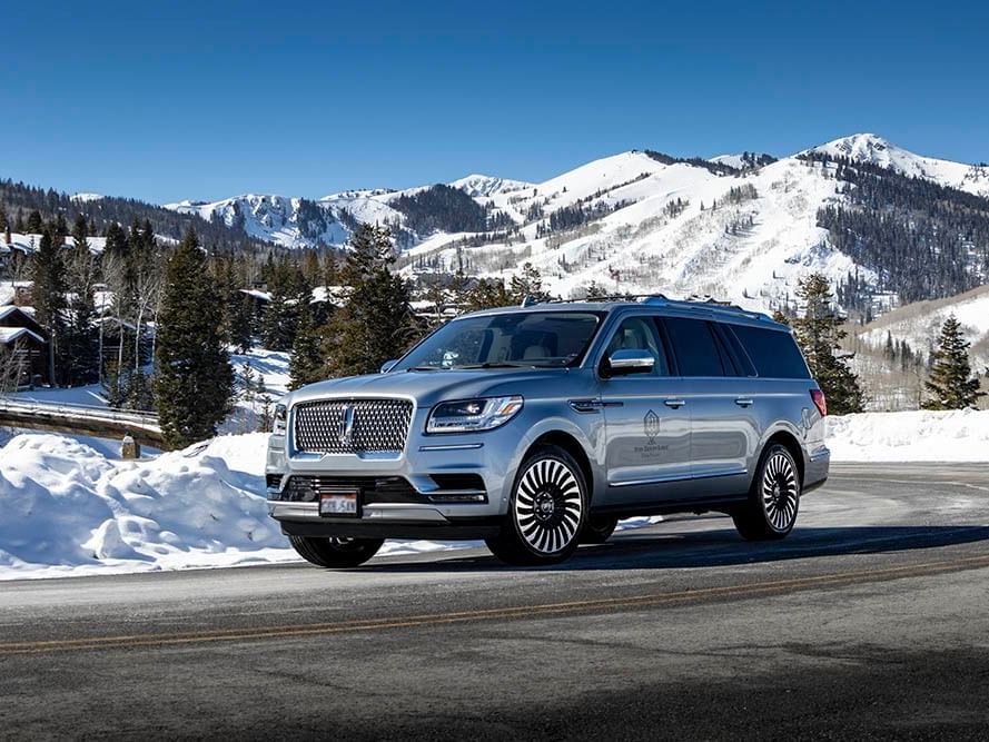 Rental Luxury Lincoln SUV of Chateaux Deer Valley on a road with snowy mountains