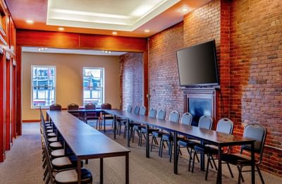Conference room featuring long tables and chairs arranged in rows facing a brick wall at Harborside Inn Boston