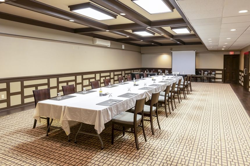 Long conference table with white linens and wooden chairs under a paneled ceiling setup at Rodd Royalty