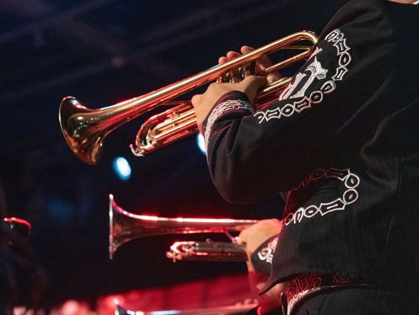 Músicos con trajes tradicionales tocando trompetas durante una presentación cerca de Camino Real Hotels