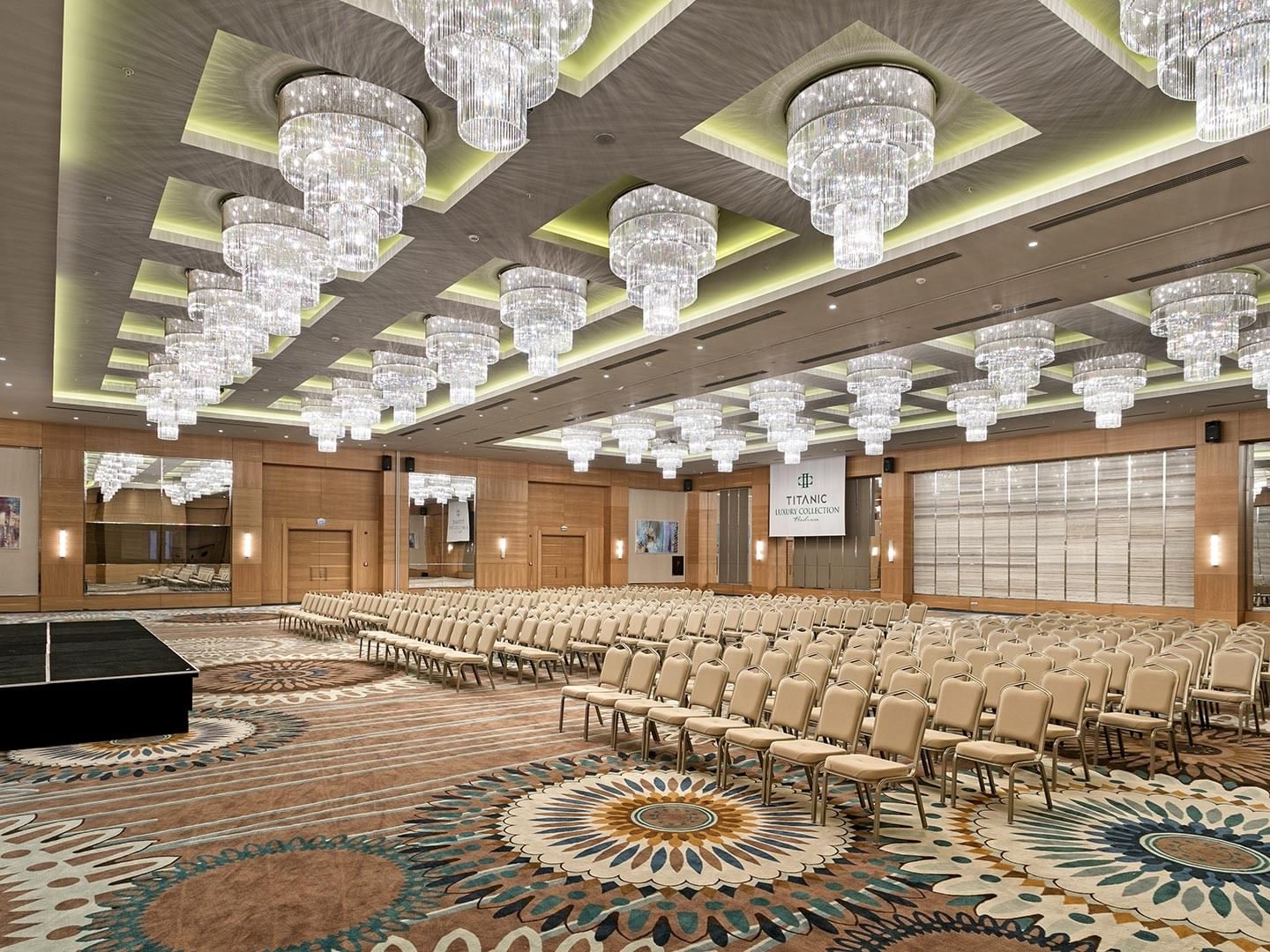Luxurious conference hall with ornate carpets and grand chandeliers at Titanic Luxury Collection Bodrum.