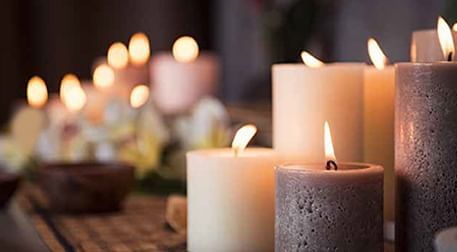 Lit candles in various shades and sizes with a soft, warm glow in Jardin Spa at DAMAC Maison Cour Jardin