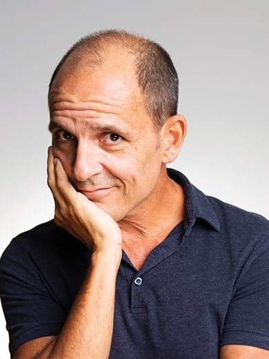 Carl Barron in a blue shirt with hand on chin for the event Just Wondering Why.