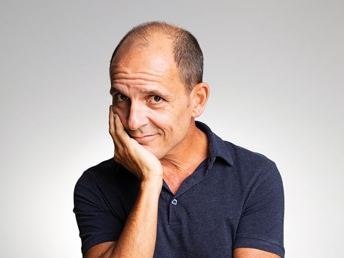 Carl Barron in a blue shirt with hand on chin for the event Just Wondering Why.