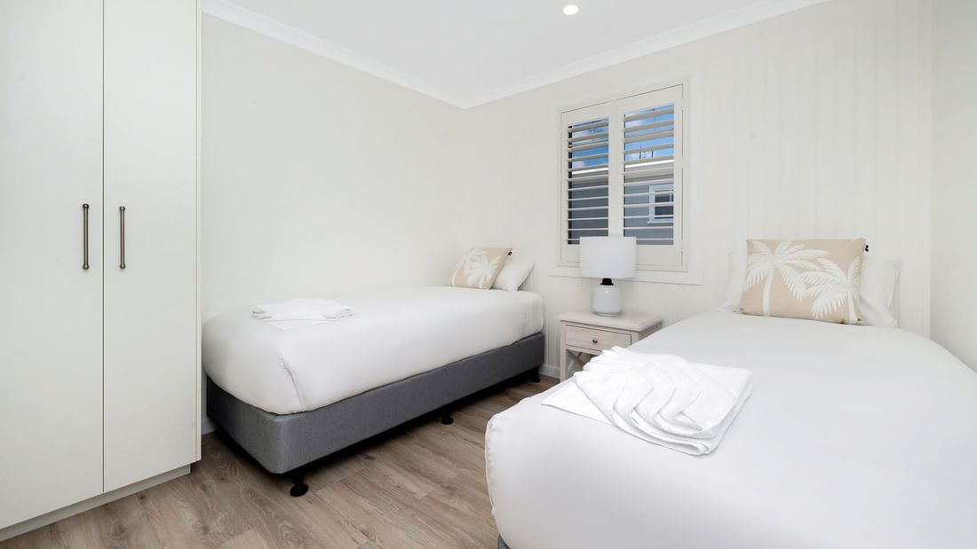 Deluxe Bungalow 2 Bedroom with two single beds, a nightstand with a lamp, and a wardrobe at Mercure Hotel Townsville
