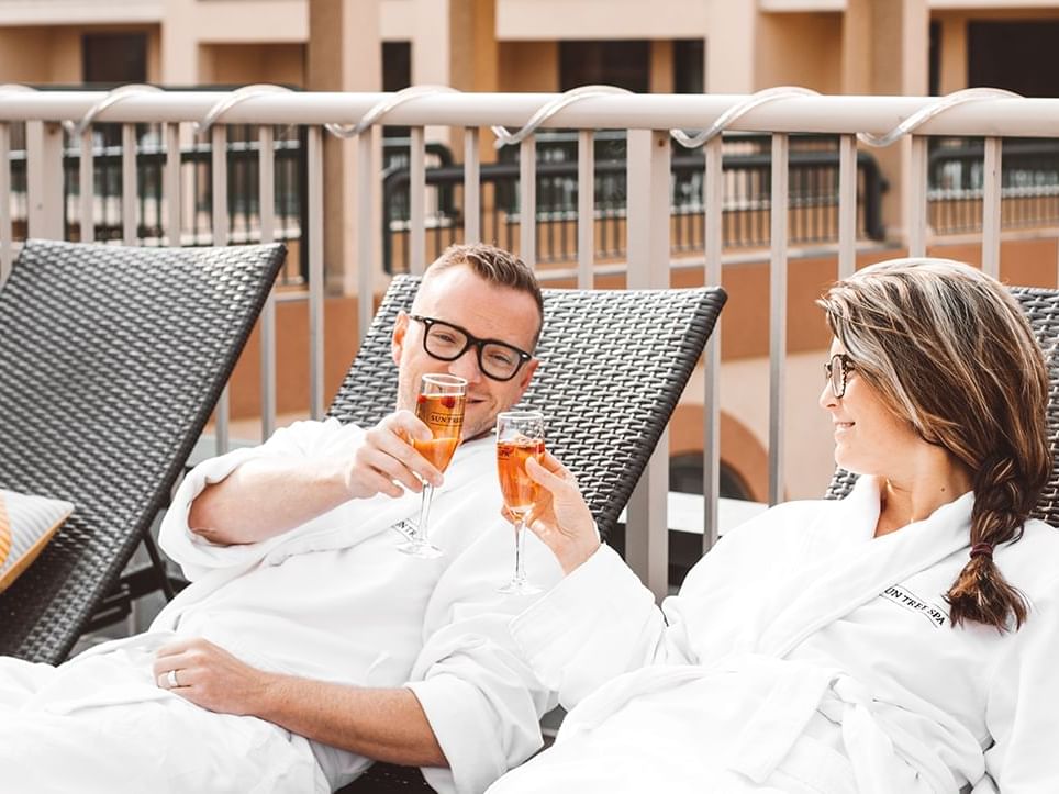 A couple toasting wine & relaxing on loungers outdoors at Temple Gardens Hotel & Spa