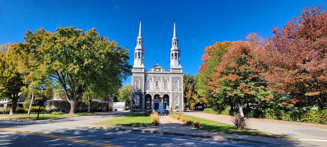 Église catholique de Montréal sous un ciel bleu avec des arbres colorés at Warwick Le Crystal Montreal