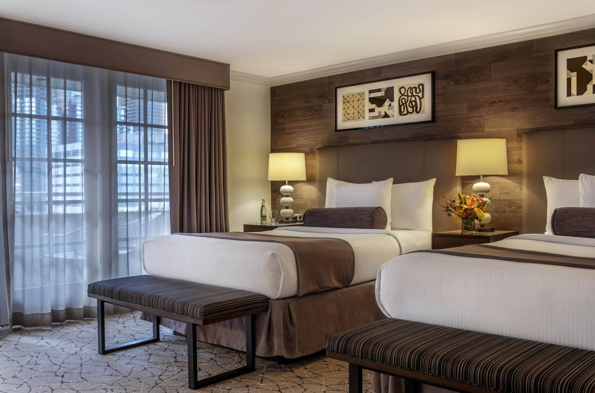 Twin beds by striped benches under a wood-paneled wall in Deluxe Rooms at Warwick Denver