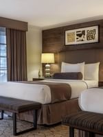 Twin beds by striped benches under a wood-paneled wall in Deluxe Rooms at Warwick Denver