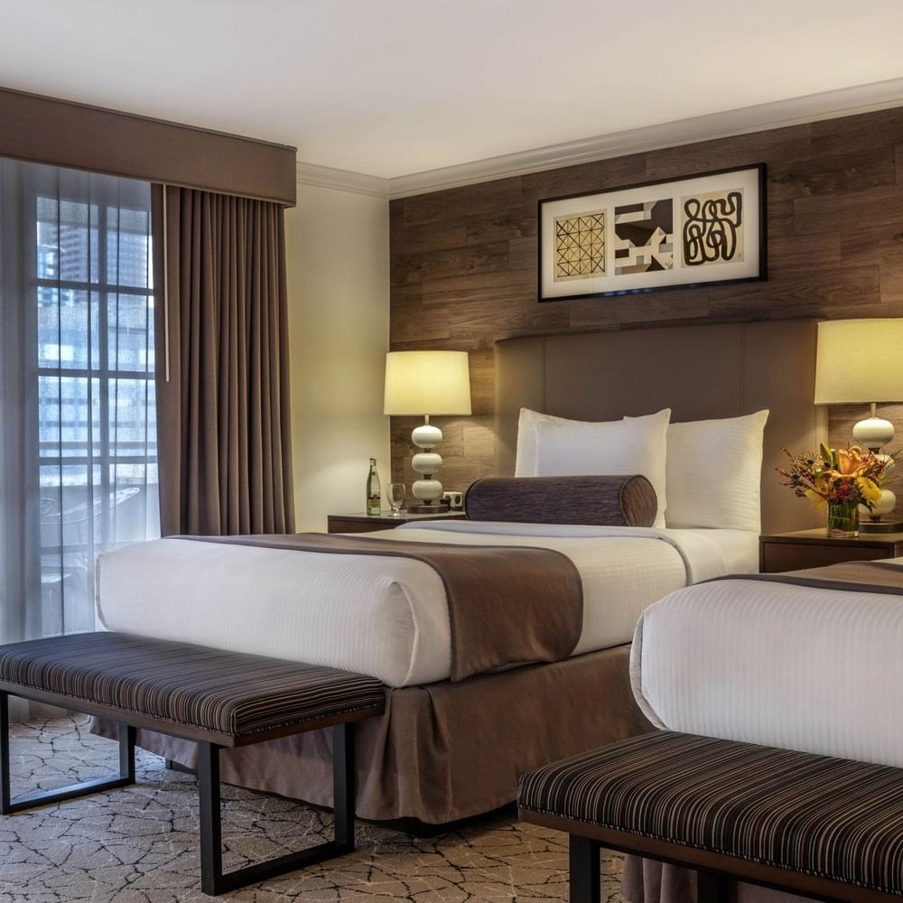 Twin beds by striped benches under a wood-paneled wall in Deluxe Rooms at Warwick Denver